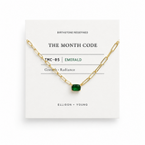 Gold necklace with a green gemstone on a 'The Month Code' card.