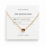 Gold necklace with a golden topaz stone on a 'The Month Code' card.