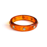 Orange tortoise bangle with embedded crystals on a white background