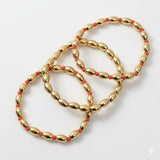 Three sets of glossy gold-tone oval bead stretch bracelets, each accented with different colored spacer beads in red, navy, or black; each set includes three coordinating bracelets.