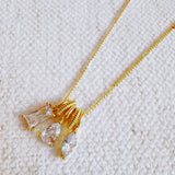 Gold-tone pendant necklace featuring a trio of stacked charms with sparkling crystal accents in a delicate layered design.