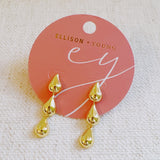 Gold-tone earrings featuring three cascading teardrop shapes in a tiered design, creating an elegant and fluid silhouette.
