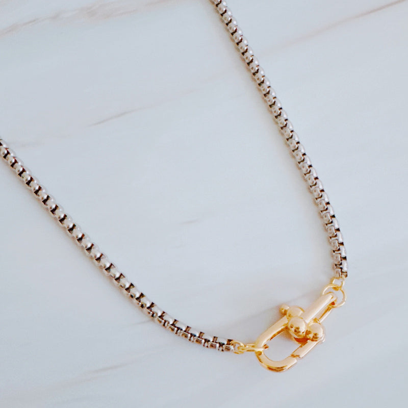 Silver-tone U-link chain necklace featuring a bold, gold lock pendant for a modern, edgy statement.