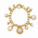 A gold charm bracelet featuring multiple white pearl elements in teardrop, square, and round settings, with a toggle clasp, photographed on a clean white background.