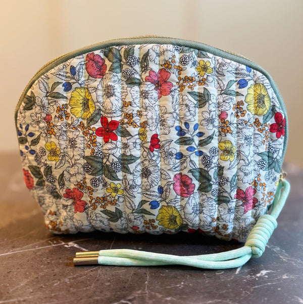 Quilted cosmetic case with a vintage-inspired floral print, featuring soft padding and a zip closure for charming and practical beauty storage.