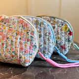 Quilted cosmetic case featuring a vintage-inspired floral print with soft padding and a structured shape, designed for storing makeup and small essentials.