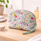 Quilted cosmetic case featuring a vintage-inspired floral print with soft padding and a structured shape, designed for storing makeup and small essentials.