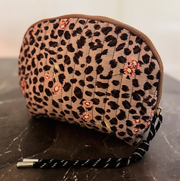 Quilted cosmetic case with a vintage-inspired leopard print design, featuring a soft padded texture and zip closure for stylish and functional storage.