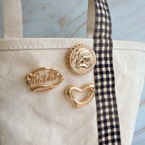 Round vintage-style brooch pin featuring a raised gold-tone medallion design of a classical female profile, bordered with beaded detailing and antique finish for an old-world charm.