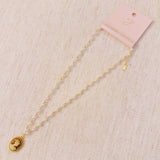 Vintage-style necklace featuring a classic cameo pendant framed in gold-tone detailing, suspended from a pearl-accented chain for an elegant and timeless look.