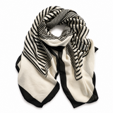 A lightweight square scarf with a black and off-white striped pattern, featuring solid black borders, arranged in a loose knot on a plain white background.