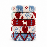 A stack of five knitted circular coasters or pads in holiday Fair Isle patterns of red, blue, and cream, arranged vertically on a white background.