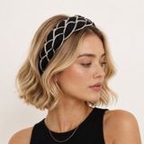 Woman wearing a black and gold headband against a white background