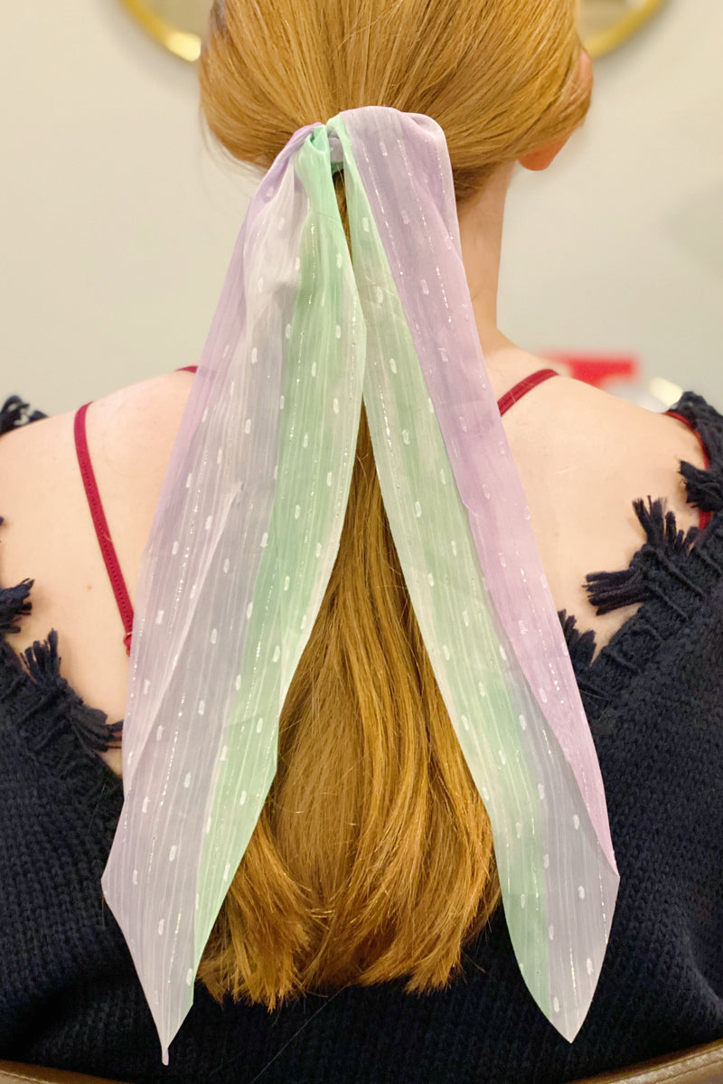 Woman with red hair wearing a green sheer scarf scrunchie in her ponytail