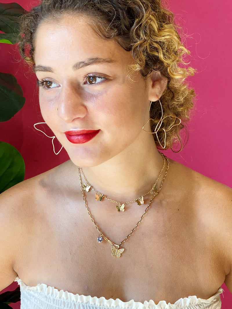 The gold Butterfly Colony Necklace styled with gold butterfly earrings and a longer butterfly necklace.