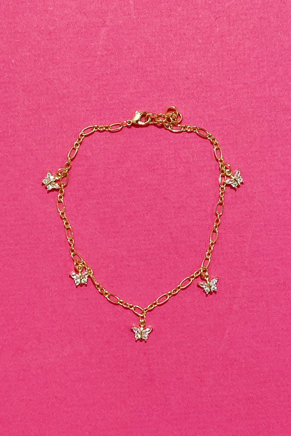 The butterfly row anklet on a hot pink background. Shows the thicker gold chain and jewel butterflies spread evenly throughout the anklet.