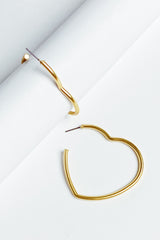 gold heart hoop earrings displayed on white jewelry holder