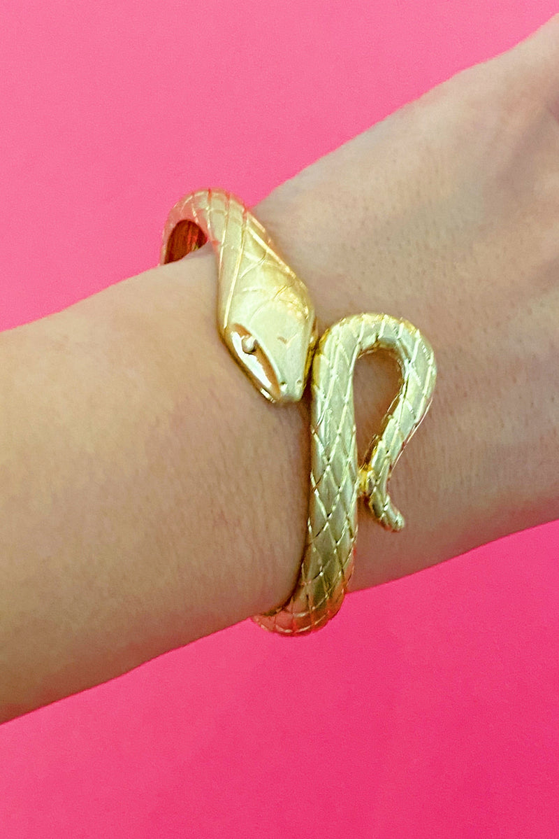 gold snake shape cuff bracelet that open and closes at the head of the snake shown on woman's wrist