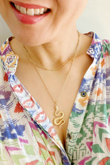 woman wearing gold double layer necklace with snake pendant