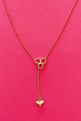 Gold chain necklace with bumble bee charm and bee hive clasps displayed on hot pink background