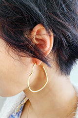 woman wearing gold heart hoop earrings